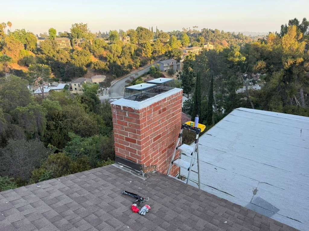 Two new chimney caps installed on a hillside home